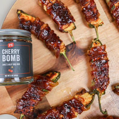 PS Seasoning Cherry Bomb Rub next to grilled jalapeno poppers that are wrapped in bacon