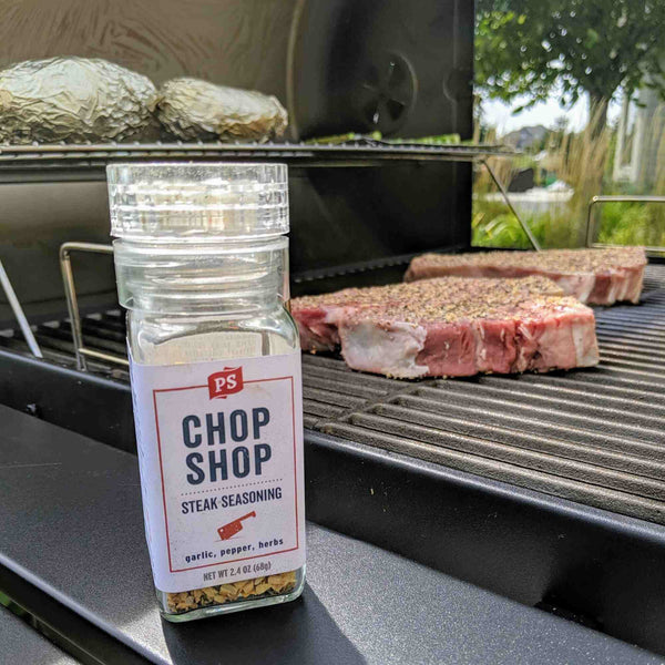 Chop Shop in front of a seasoned steak on the grill.