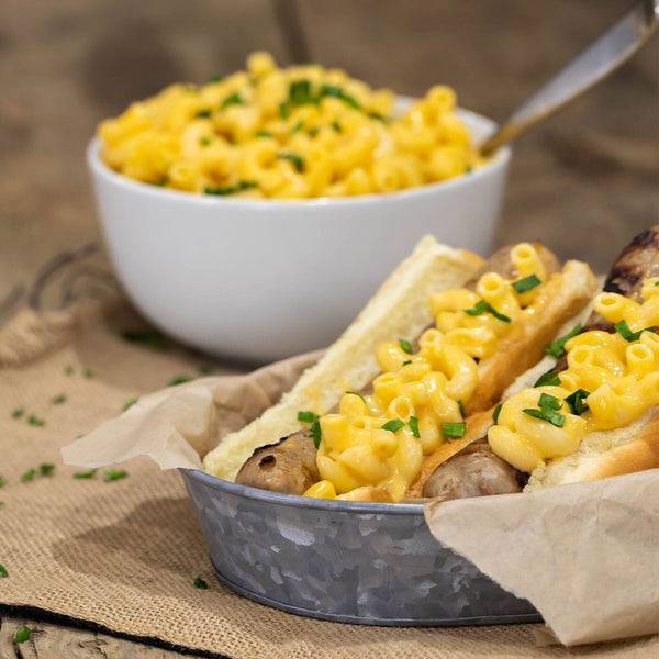 Mac and Cheese Bratwurst next to a bowl of mac and cheese.