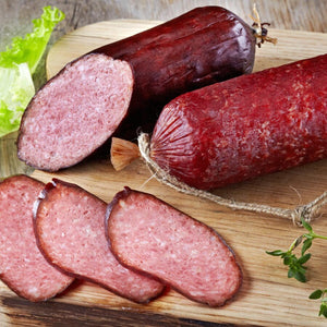 Logs of Summer Sausage with three slices front and center.