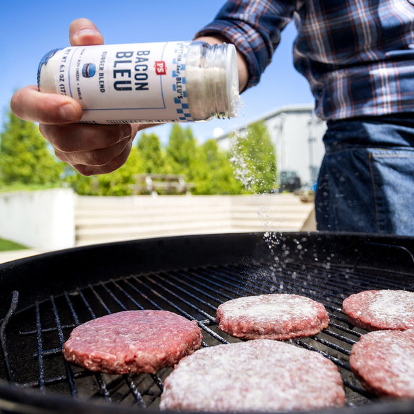 Bacon Bleu Burger Blend sprinkled on burger patties on the grill.