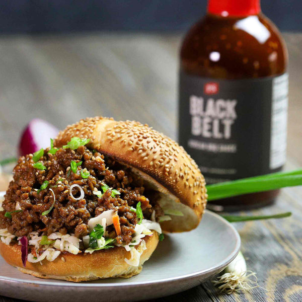 A plate of Korean BBQ Sloppy Joes in front of a bottle of Black Belt - Korean BBQ