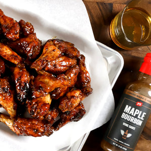 PS Seasoning's bourbon BBQ sauce used as a chicken wing sauce next to a basket of coated wings and a beer.
