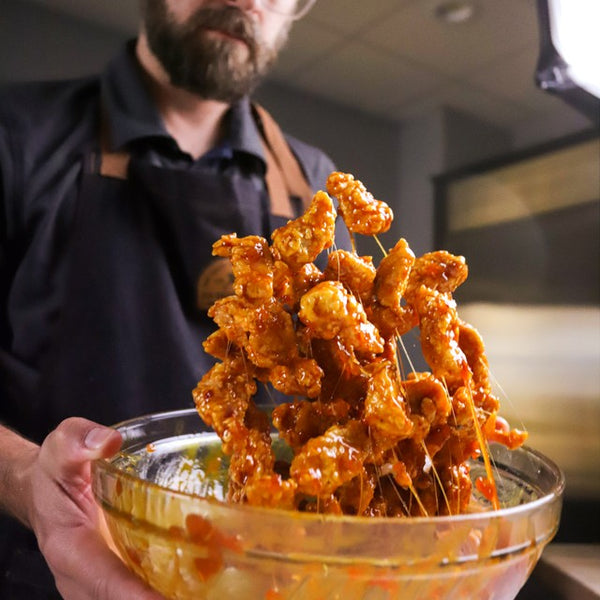 Pineapple Sriracha Wings being tossed in a bowl to fully coat the wings.
