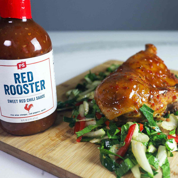 Sweet Chili Glazed Duck laying on a bed of veggies. This meal is next to a bottle of Red Rooster - Sweet Red Chili Sauce