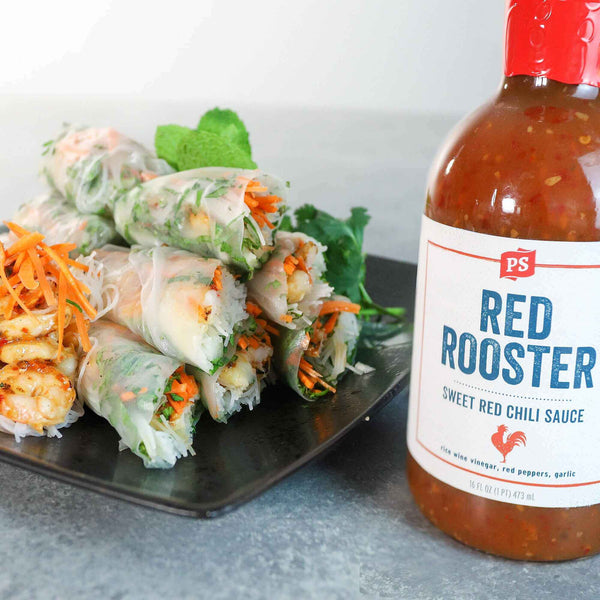 Shrimp Spring Rolls next to a bottle of Red Rooster - Sweet Red Chili Sauce