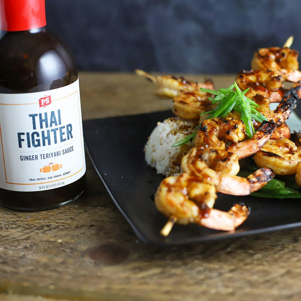 Shrimp skewers next to a bottle of Thai Fighter