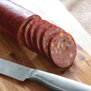 Cut up Jalapeno Summer Sausage sitting on a cutting board next to a knife.