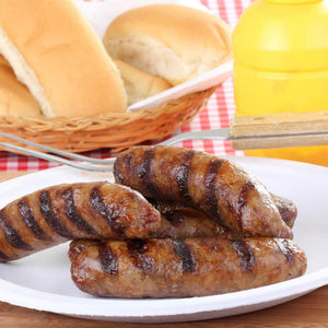 Delicious plate of brats set on a picnic table with a basket of buns behind.