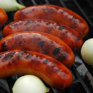 Sriracha & Onion Brats sizzling on the grilled along with whole onions.