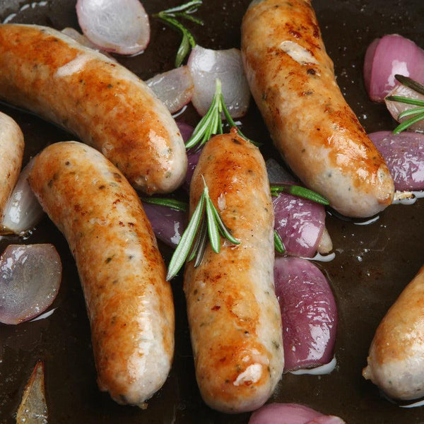 Fresh Pork Sausage in a pan with cooked onions.