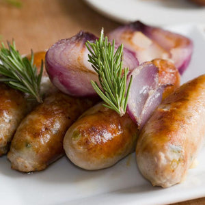 French Onion Brats on a plate with onions on top of them.