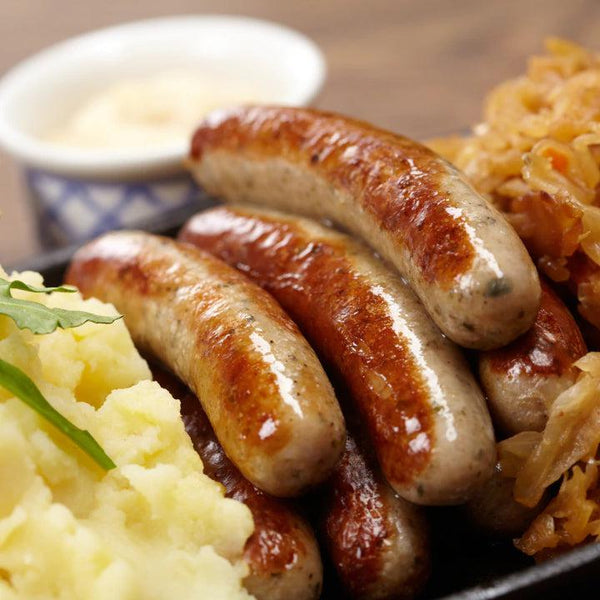 Pile of English Banger Sausage next to carnalized onions and mashed potatoes.