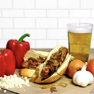 Badger Brat with onions on top of it surrounded by ingredients and a beer.
