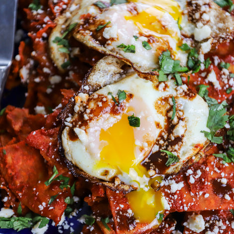 tortillas in a red sauce with fried eggs