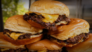 Smoked smash burgers with melted American cheese on a griddle
