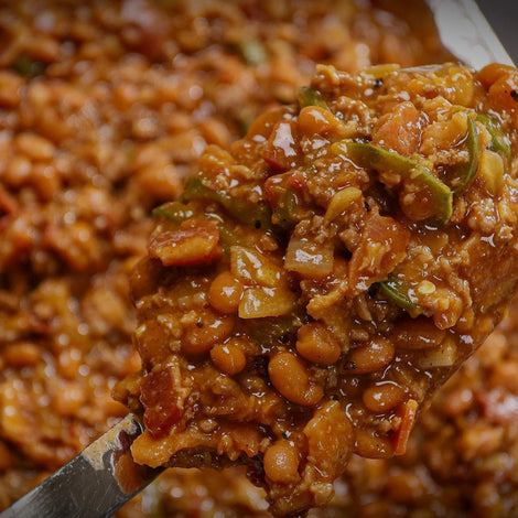 Smoked baked beans in a foil pan loaded with bacon and ground beef