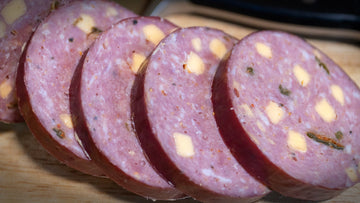 Jalapeno cheddar summer sausage sliced on a cutting board showing melted cheese pockets