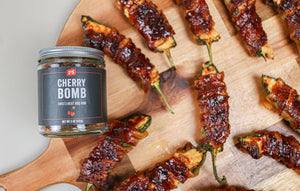 PS Seasoning Cherry Bomb Rub next to grilled jalapeno poppers that are wrapped in bacon