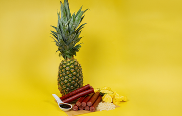 Pineapple Teriyaki Snack Sticks made with PS Seasoning No. 853 Pineapple Teriyaki Snack Stick Seasoning, shown with fresh pineapple, teriyaki sauce, and cooked rice on a yellow background.