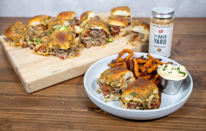 Baked cowboy sliders made with ground beef, bacon, fried onions, and melted cheese on Hawaiian rolls, seasoned with PS Seasoning Backyard Blend, served with sweet potato fries and aioli.