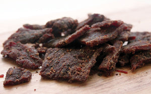 Beef jerky strips soaking in a homemade from-scratch brine — bulk DIY jerky brine recipe using salt, sugar and pink cure