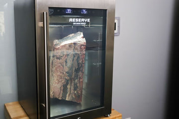 Reserve 50 dry aging cabinet on a kitchen counter with beef primal aging inside, digital display showing temperature and humidity