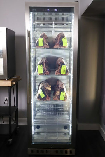 Fully loaded Reserve dry aging cabinet with multiple beef cuts properly spaced on hooks and shelves for optimal airflow and yield