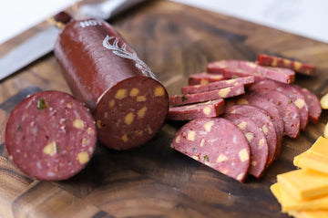 Jalapeño cheddar venison summer sausage sliced with cheese on board – perfect for wild game charcuterie and snack trays