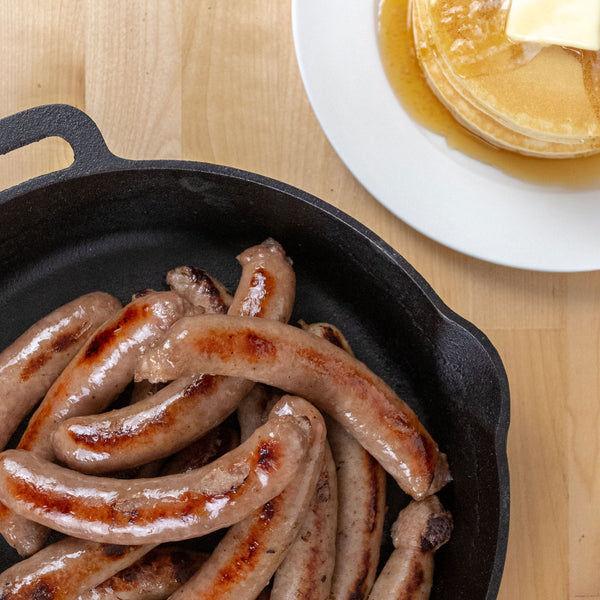 Pancake Breakfast Sausage next to a stack of buttered pancakes.