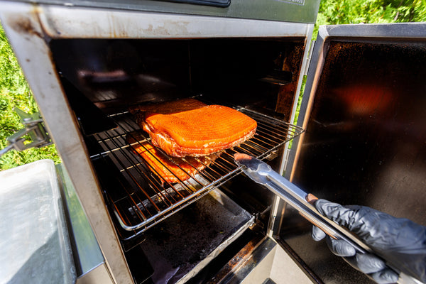 smoked bacon being taken out of a smoker