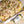 Platter of pasta with cheese and ham next to a container labeled 'Black Gold' on a wooden surface.