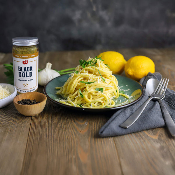 Plate of pasta with lemons and 'Black Gold' seasoning on a wooden table