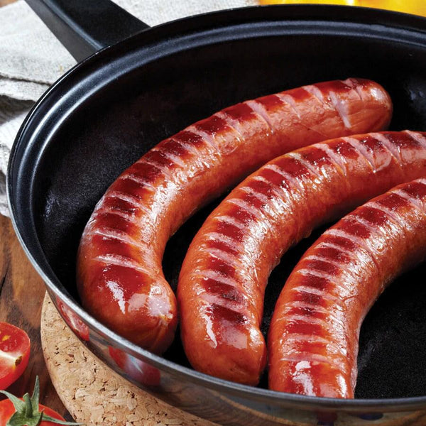 Three Chili Dogs sizzling in the pan.