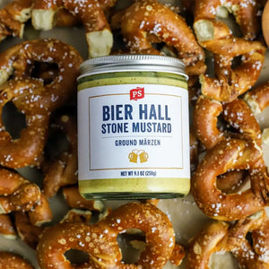 A jar of Bier Hall Stone Mustard laying on a bed of pretzels