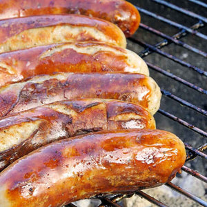 Six Jalapeno Brats sizzling on the grill getting ready to be eaten. 
