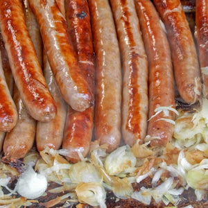 A pile of Hot Pork Sausages laying on a bed of onions.