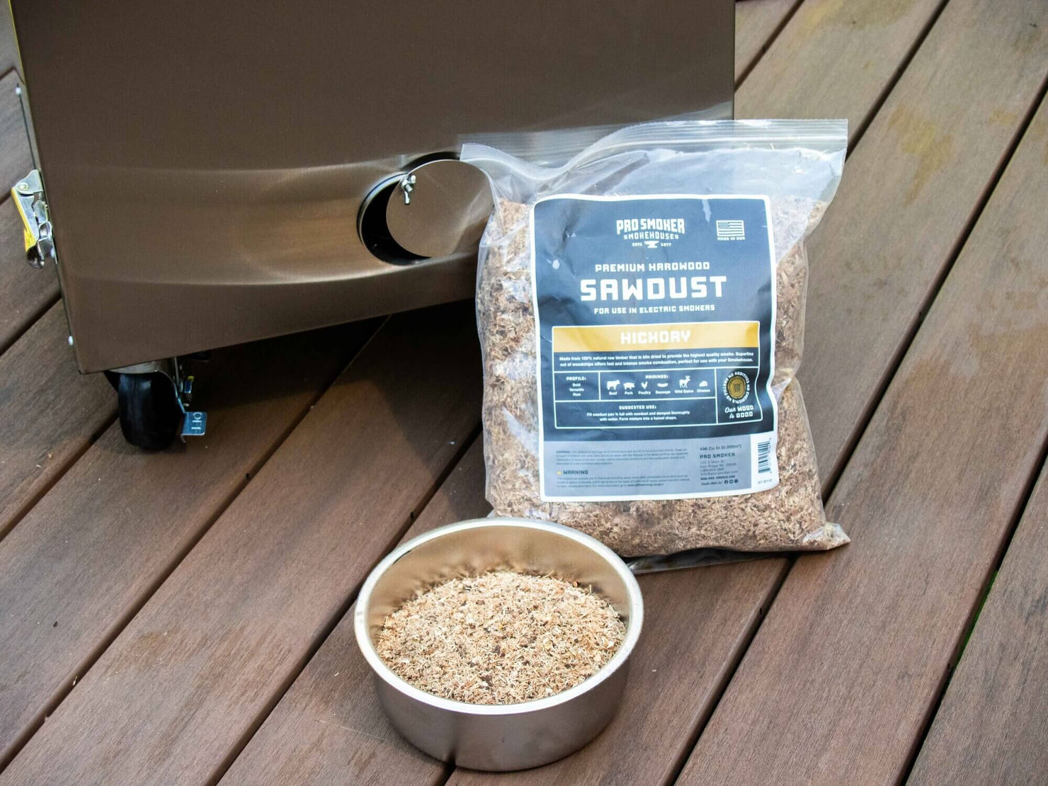 Bag of sawdust and a bowl on a wooden surface next to a smoker.