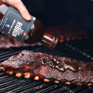 Blue Ribbon being poured on a rack of ribs that are on the grill.