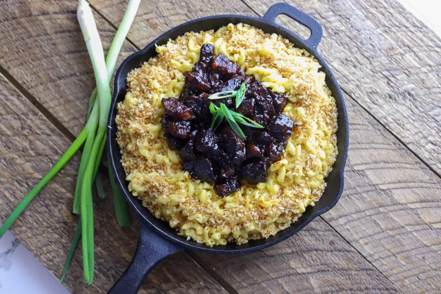 Skillet with burnt ends mac 'n cheese on a wooden surface