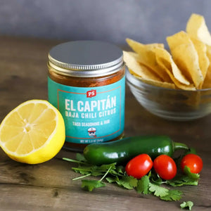 Can of El Capitán next to a bowl of chips, tomatoes, basil, a jalapeno, and a lemon