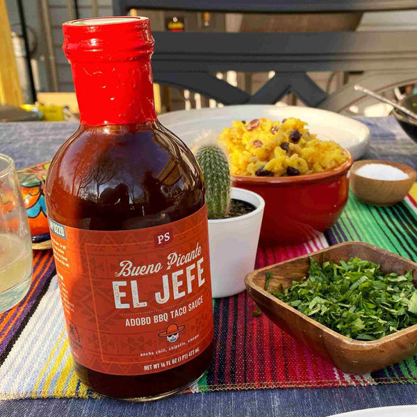 El Jefe  on a table next to a bowl of greens, rice, and a cactus