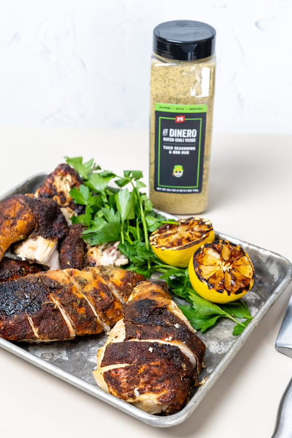Grilled chicken with lemon and herbs on a tray with a seasoning bottle labeled 'El Dienero'.