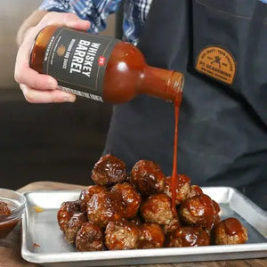 Whiskey Barrel BBQ sauce being poured on a plate of meatballs