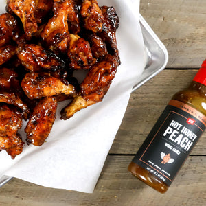 Hot Honey Peach Wing Sauce next to a plate of chicken wings