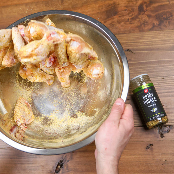 Spicy Dill Pickle Wing Rub being tossed with chicken legs and wings