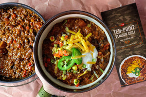 Bowl of chili with toppings next to a package of Ten Point Venison Chili seasoning mix.