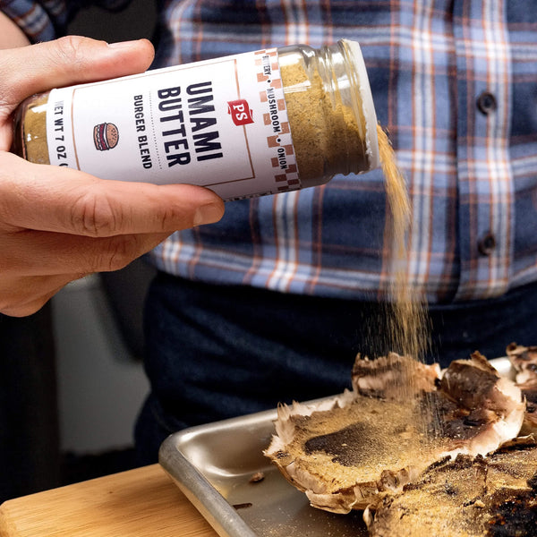 Person sprinkling Umami Butter blend from a jar onto a piece of food.