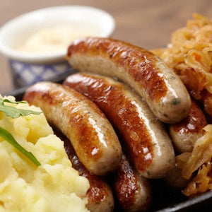 Pile of English Banger Sausage next to carnalized onions and mashed potatoes.